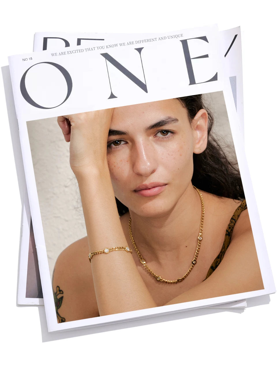 A close-up photo of a woman wearing a gold stainless steel charm necklace on her neck and wrist.