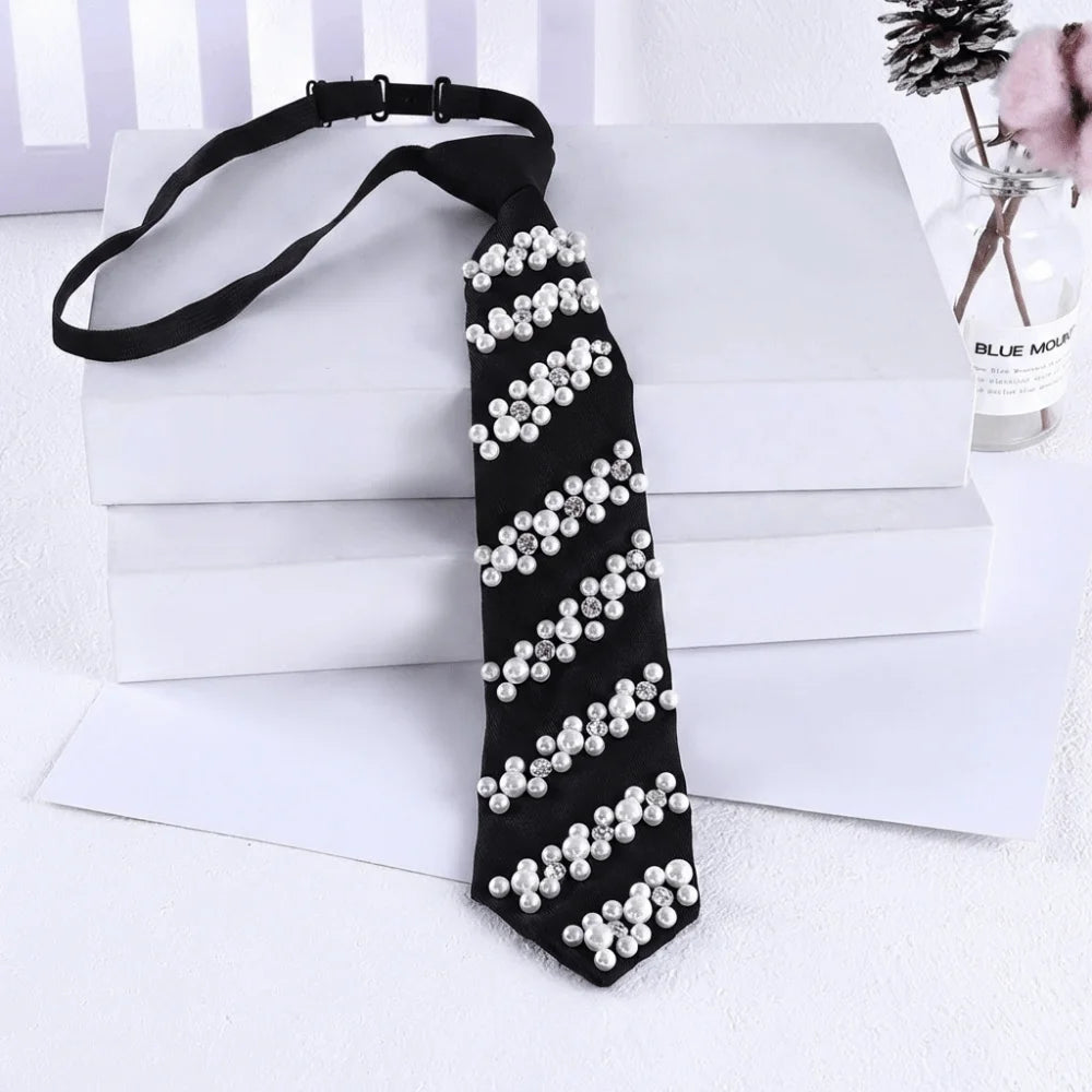 Black tie adorned with white pearls and rhinestones displayed on a stack of white books.