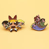 A pair of retro cartoon enamel lapel pins featuring stylized characters with dark hair and expressive faces.