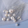 A set of 18 faux pearl hair pins with delicate wire stems displayed on a light blue fabric.