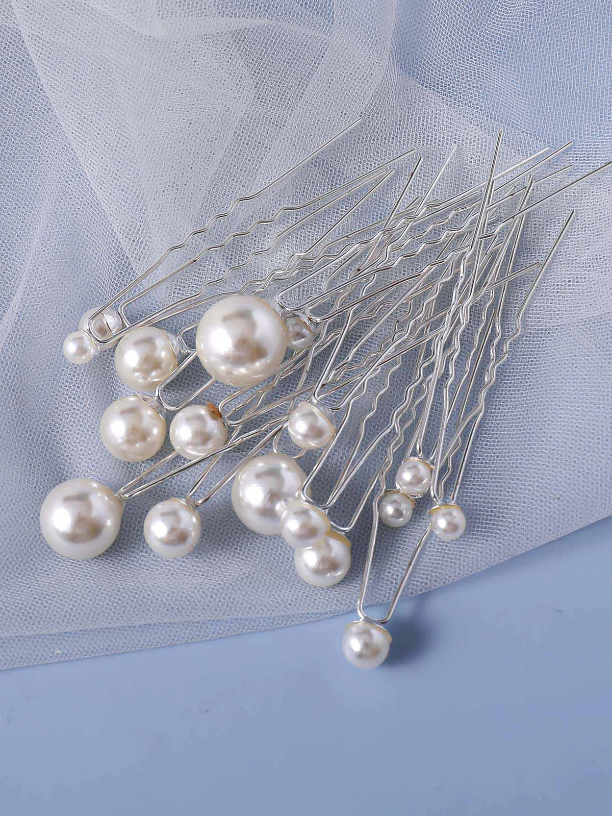 A set of 18 faux pearl hair pins with delicate wire stems displayed on a light blue fabric.