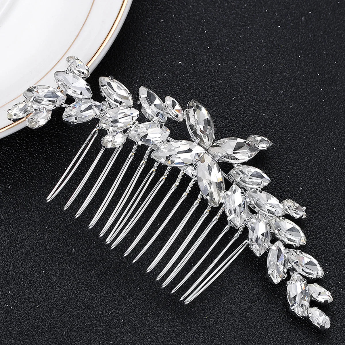 Une délicate peigne pour cheveux de mariée en cristal avec de longues pointes, présentée sur une surface sombre.