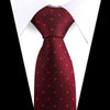 A close-up of a red patterned silk necktie worn under a white dress shirt.
