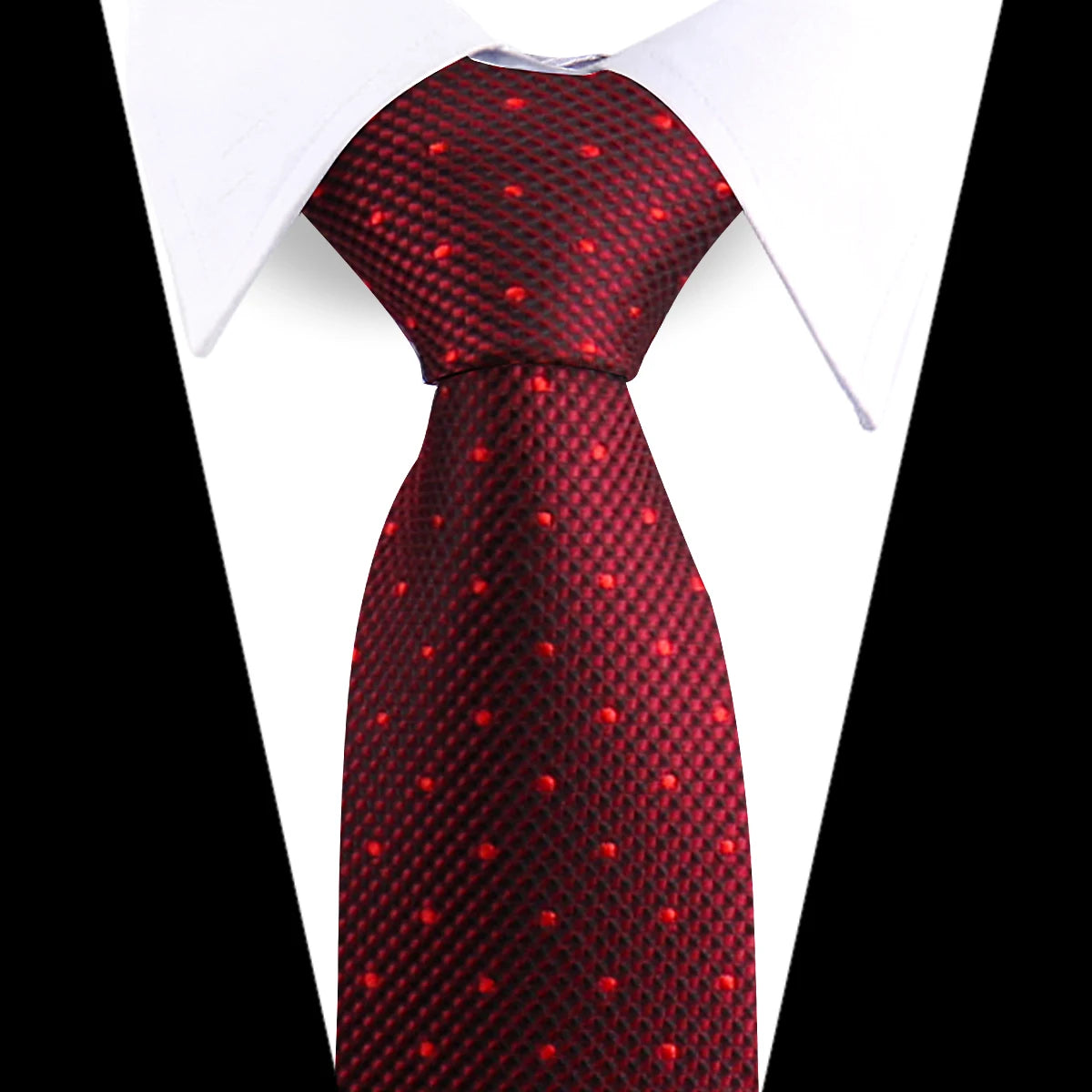 A close-up of a red patterned silk necktie worn under a white dress shirt.