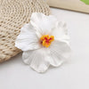 A white hibiscus flower with a yellow center rests on a woven natural fiber mat.