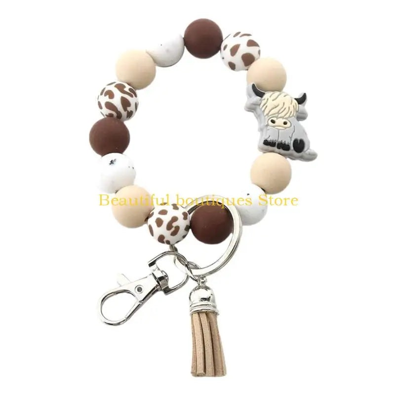 A keychain featuring a silicone charm shaped like a Highland cow, with various brown and white round charms.