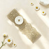 A vintage polka dot button headband displayed on a light background with white daisies and lace fabric.