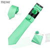 Conjunto de corbata de seda verde menta con pañuelo de bolsillo a juego y un broche floral verde decorativo.