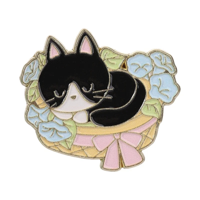 A black cat face design set within a floral wreath and pink bow enamel brooch