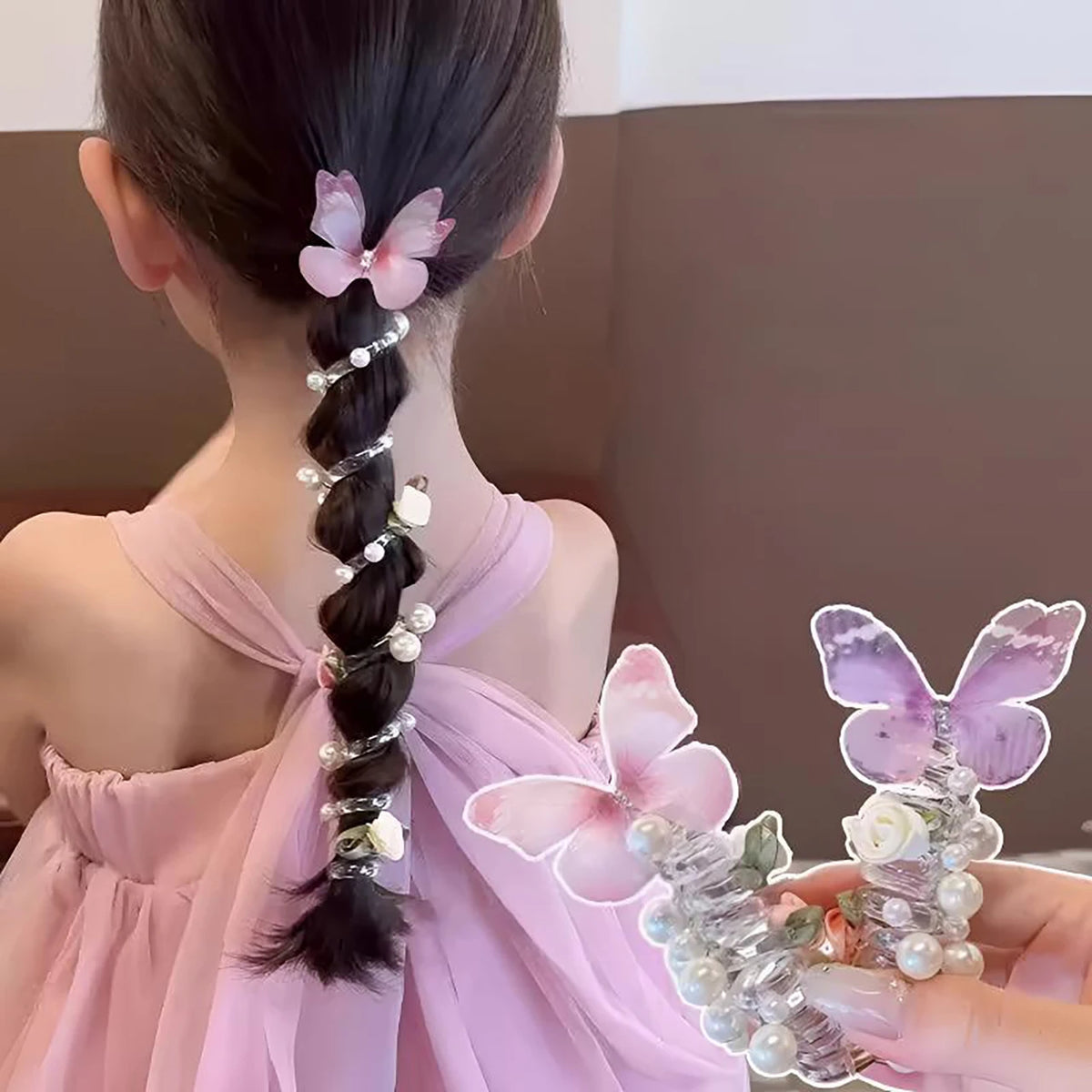 A woman's back shows a long black braided hairstyle adorned with pink butterfly hair ropes and pearl accents.
