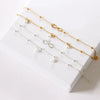 A collection of delicate silver-plated friendship anklets with various charms displayed on a white surface.