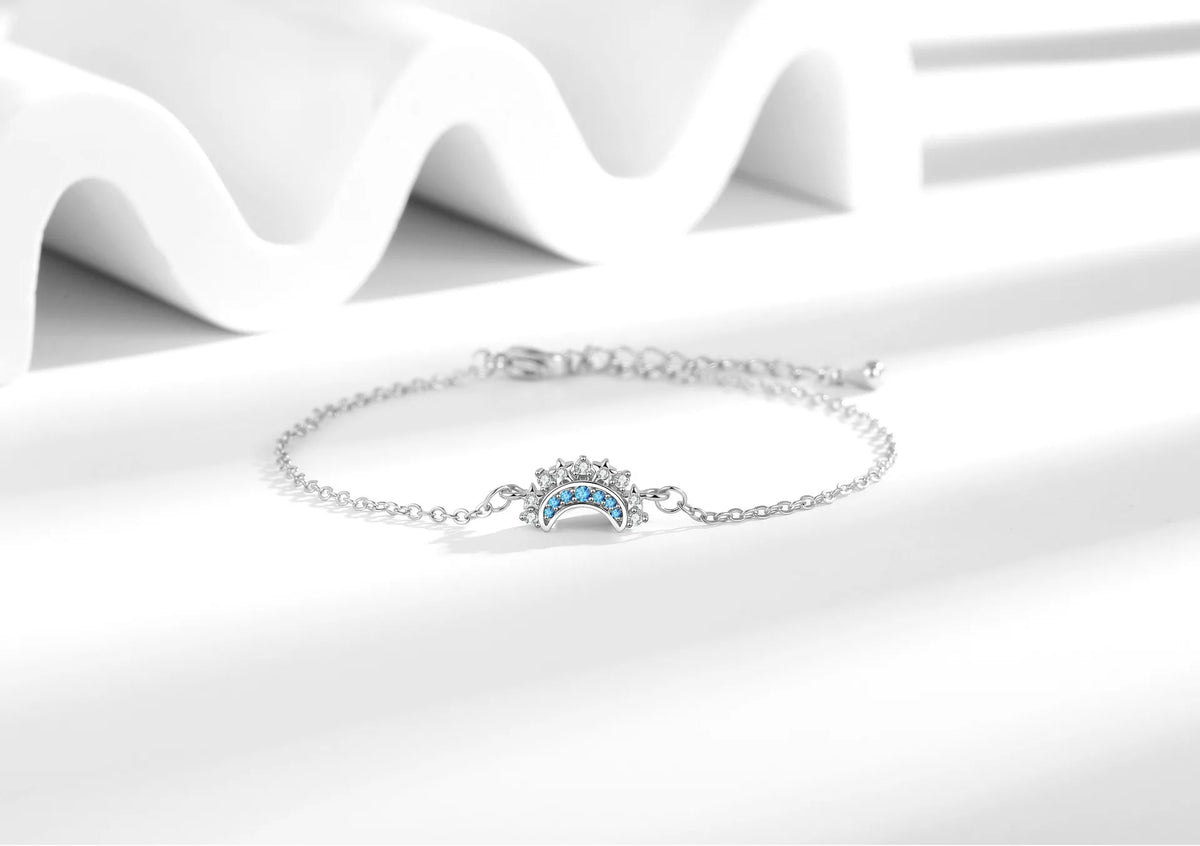 Silberne, verstellbare Armbänder mit blauen Sonne- und Mond-Anhängern auf weißem Untergrund.