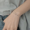 A close-up of a Sterling Silver double heart charm bracelet worn on a wrist against a light gray shirt.