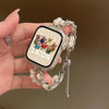 A hand holds a smartwatch with a beaded strap and charm, displaying the time 16:05.