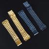 Drei Armbänder zur Uhr: goldfarben, dunkelblau und schwarz, diagonal auf dunklem Hintergrund.
