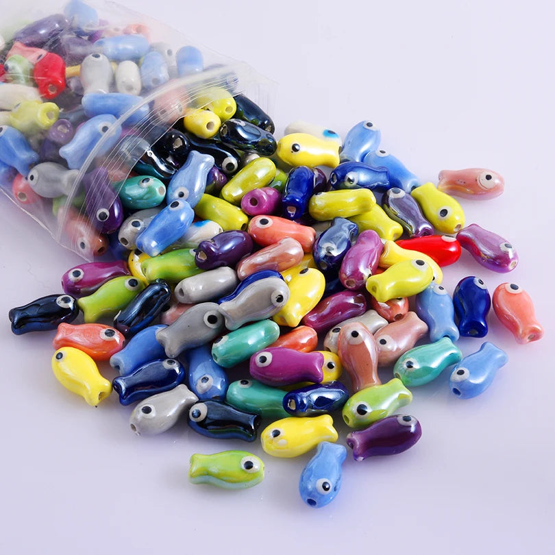 Assortment of colorful ceramic fish charms for DIY jewelry, displayed in a clear plastic bag.
