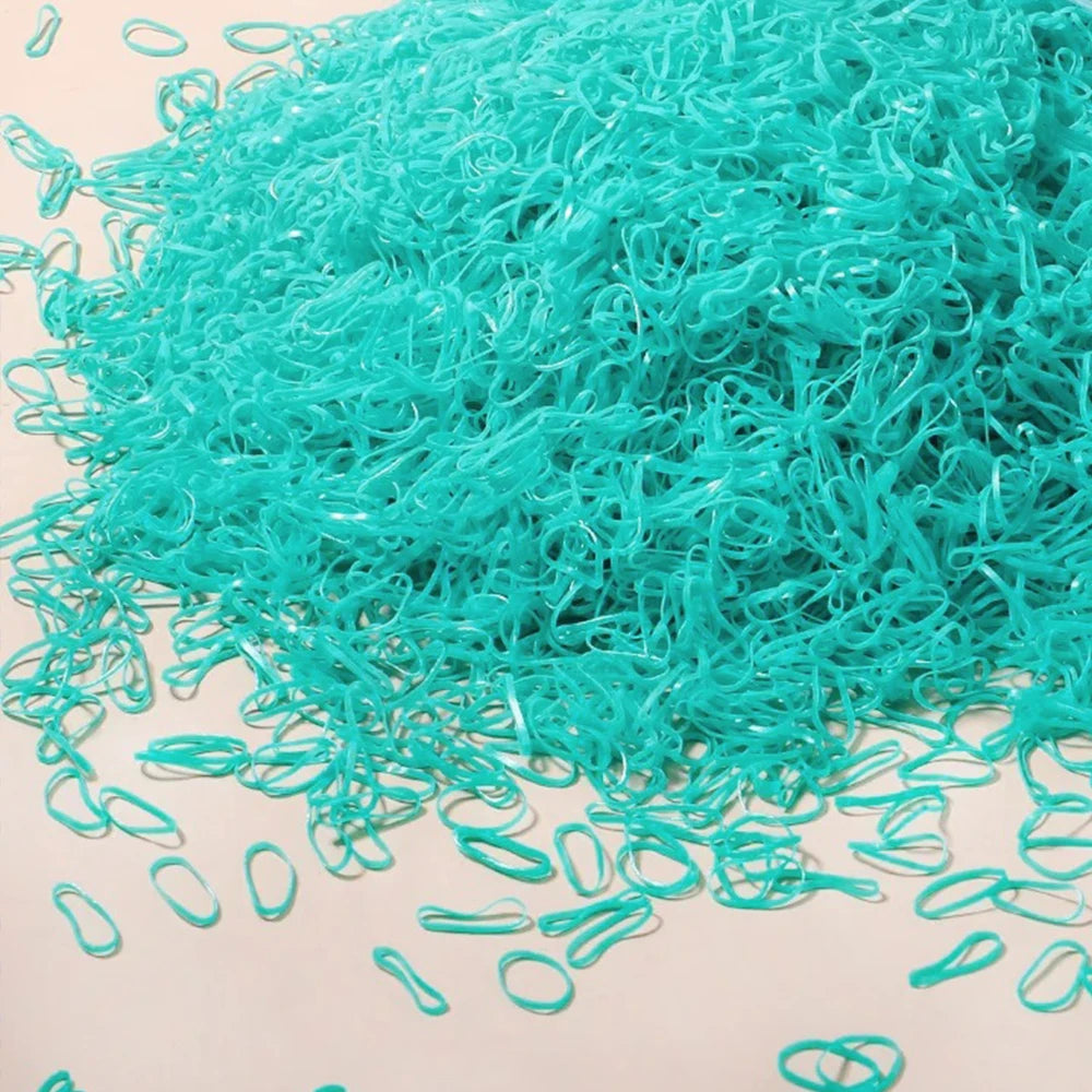 A pile of bright turquoise disposable rubber hair ties for kids scattered on a light surface.