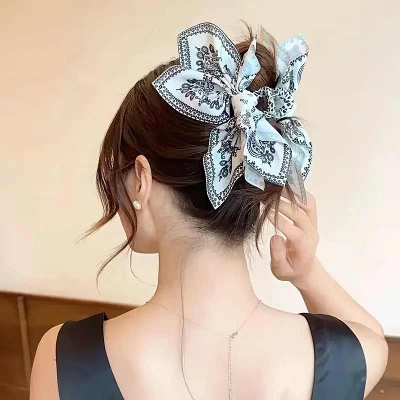El cabello oscuro de una mujer está adornado con una elegante pinza de cabello estilo cashew vintage con tela floral azul cla