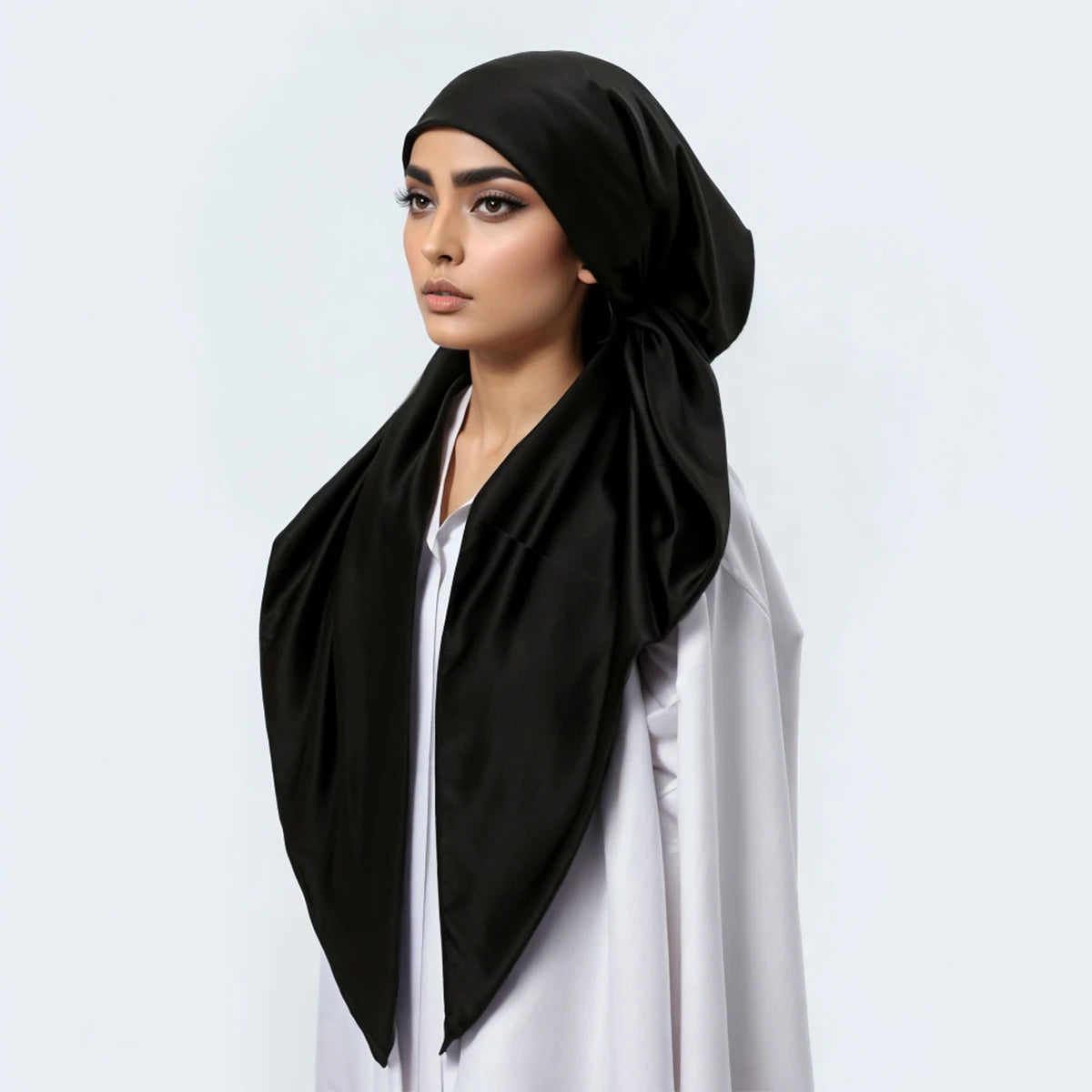 A woman wearing a black satin silk hijab headband cap with a white top.