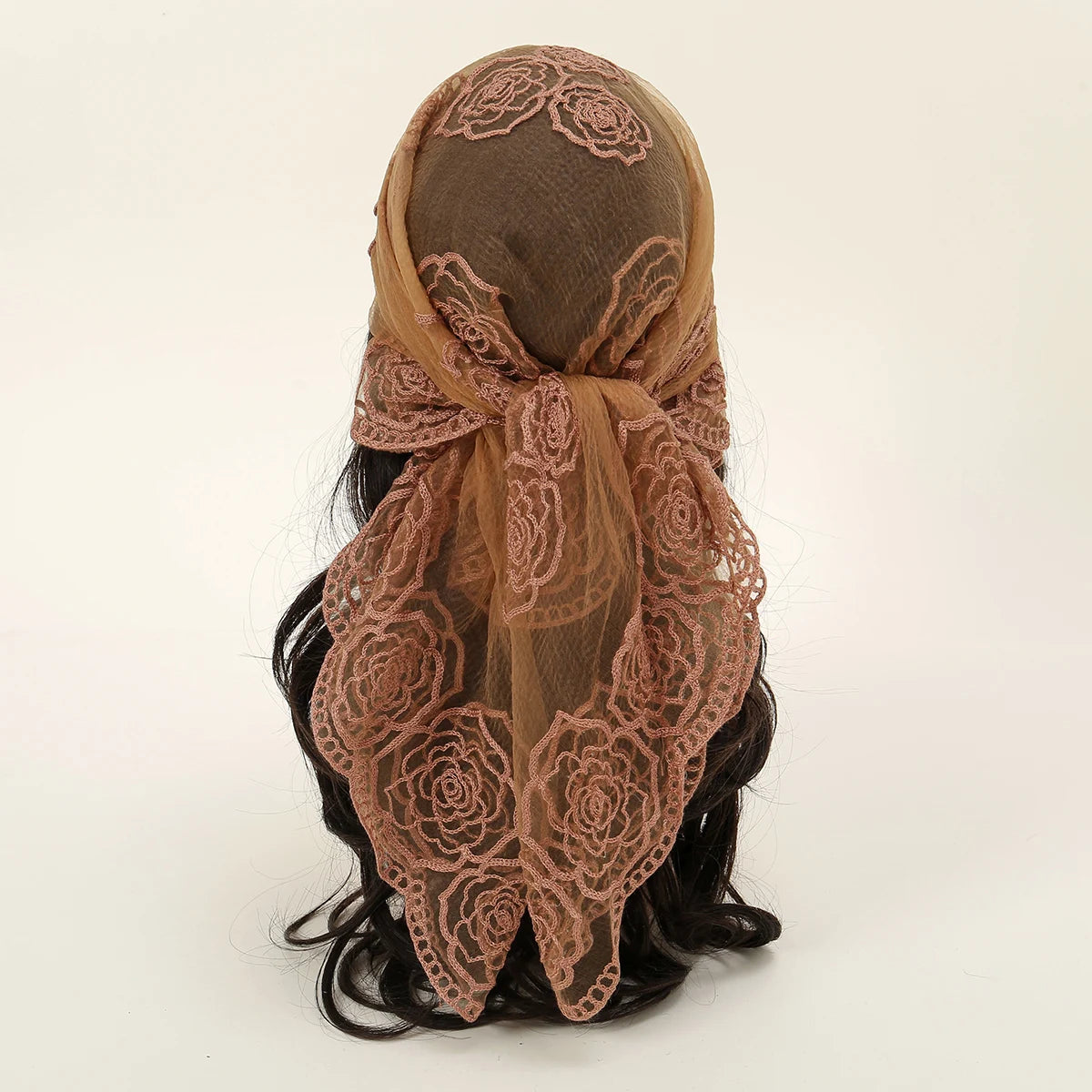 A close-up of a floral embroidered lace bandana headscarf tied around dark hair.