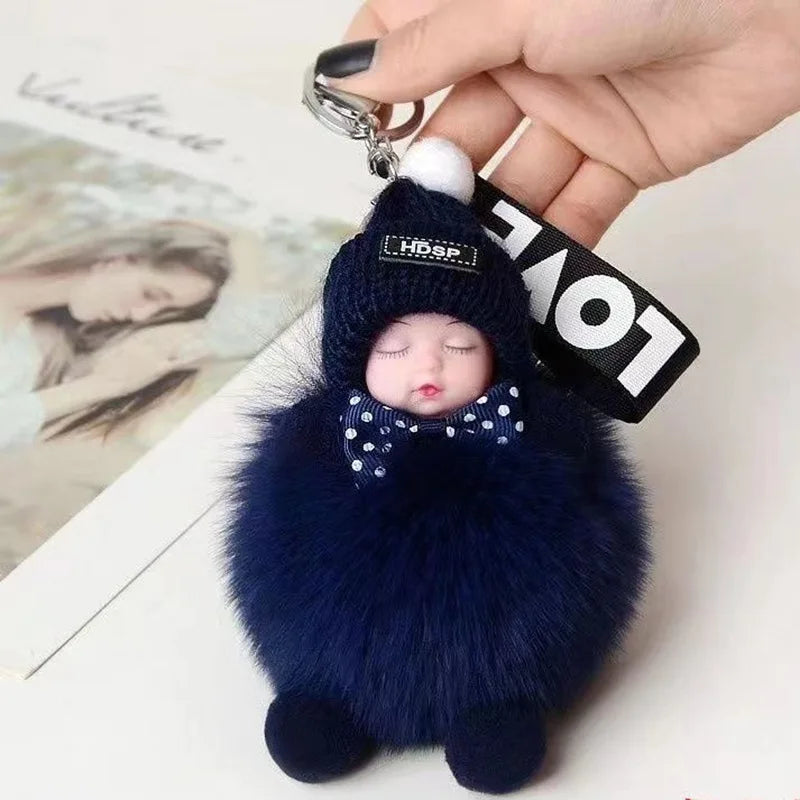 A dark blue fluffy cartoon plush doll with a bow and headphones attached to a keychain.