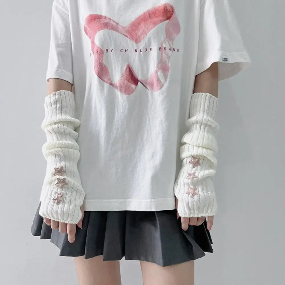 A person wearing a white t-shirt and a black skirt, featuring white fingerless arm warmers with small star details.