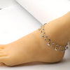 A close-up of a hand wearing a stainless steel anklet with blue rhinestone pendants on the ankle.