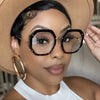 A woman wearing tortoiseshell anti-blue light eyeglasses and a straw hat.