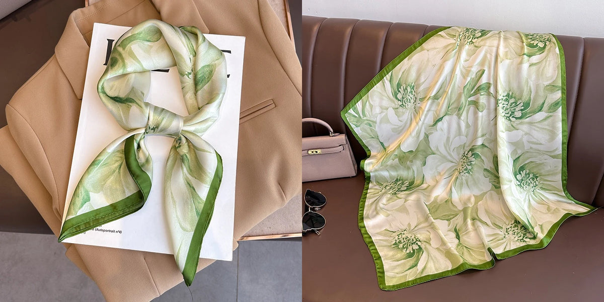 A light green and gold floral print silk scarf draped on a beige blazer next to a small handbag.