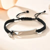 Silber-Edelstahl-Paararmband-Set mit schwarzem Schnur und Herz-Anhängern auf heller Oberfläche.