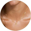 A close-up of a gold plated alphabet initial necklace resting on the skin of a person's neck.