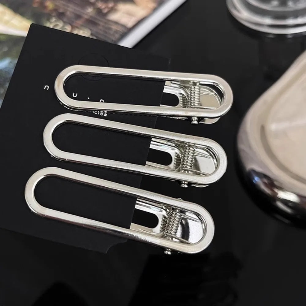 A set of three vintage silver Y2K metal hair clips displayed on a black card.