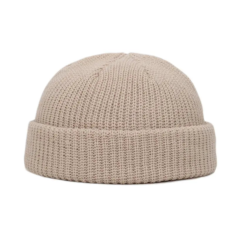 A beige knitted beanie cap with a ribbed cuff shown from the front.