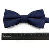Navy blue bow tie and suspenders set with a ribbed texture displayed above a ruler.