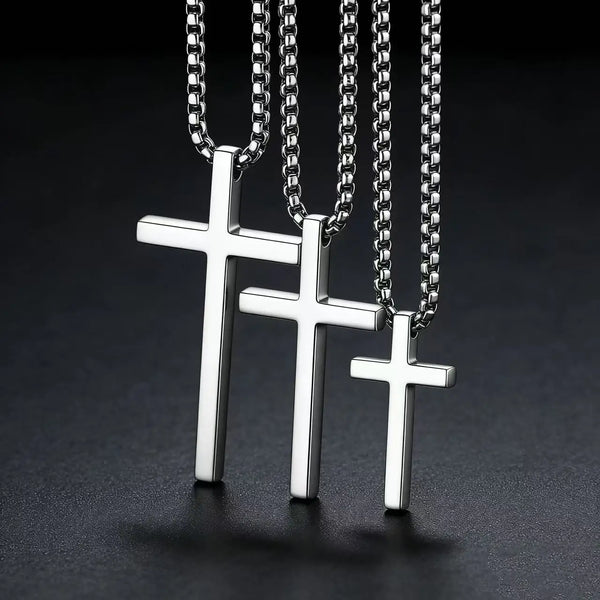Trois colliers pendentifs en croix en acier inoxydable argenté, suspendus verticalement sur un fond sombre