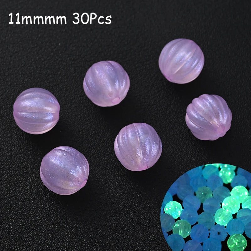 Thirty 11mm luminous glow-in-the-dark acrylic beads scattered on a dark surface with a close-up of blue and green glowing bea