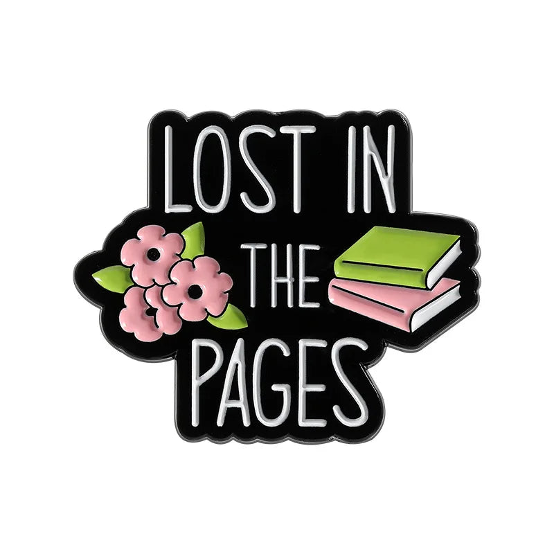 Black enamel lapel pin with text that reads Lost in the Pages surrounded by pink flowers and a green book.