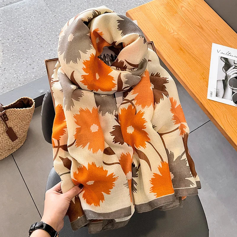 Gefaltener Luxus-Baumwoll-Pashmina-Schal in Orange- und Beige-Tönen auf einem Holztablett.