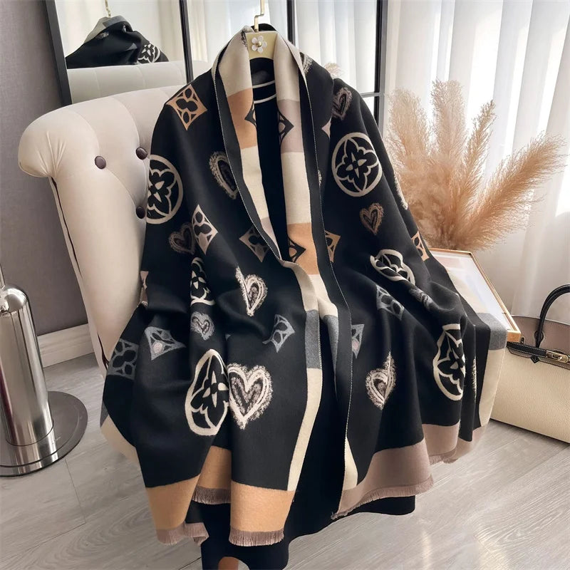 A black and beige plaid cashmere scarf and shawl wrap draped over a white chair.