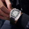 A hand is holding a black quartz watch with a clear crystal and silver dial on a wrist.