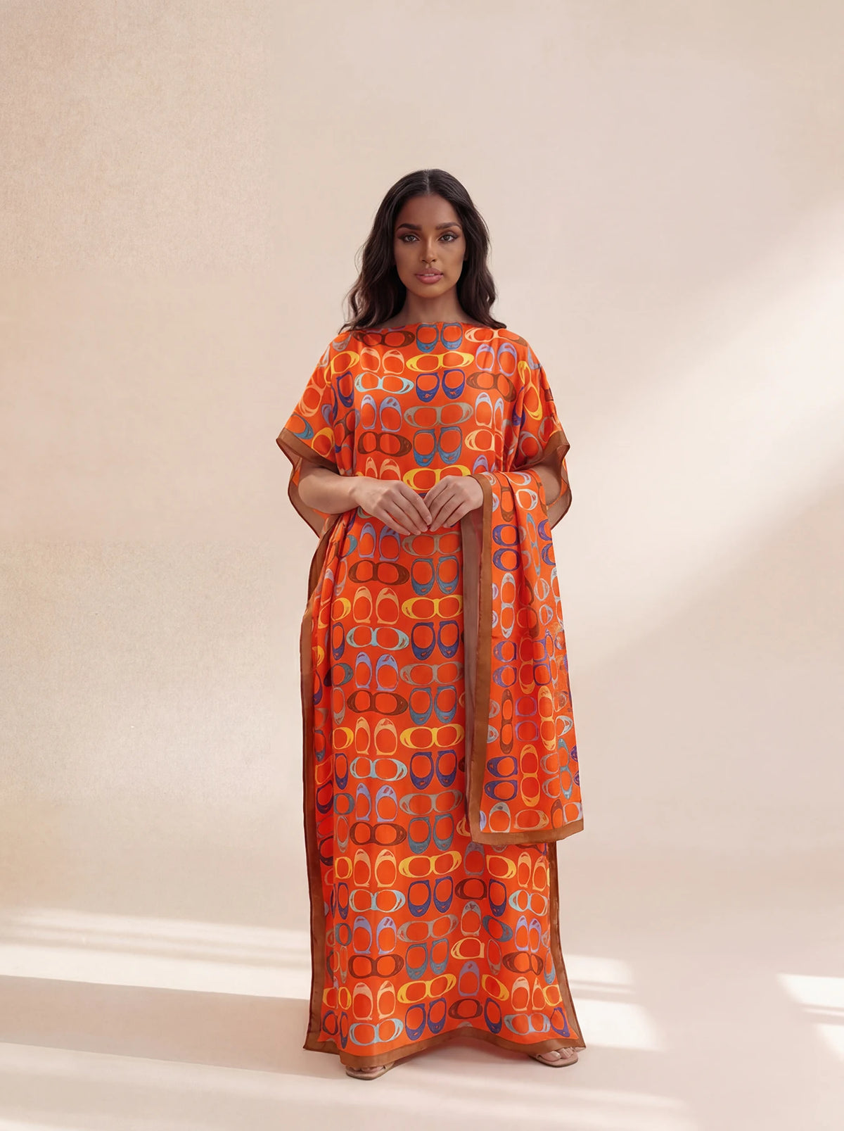 A woman models an orange and blue patterned long silk blend cover-up robe dress.