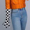 A close-up of a person wearing orange leather jacket, a wide belt, and black and white checkered latex gloves.