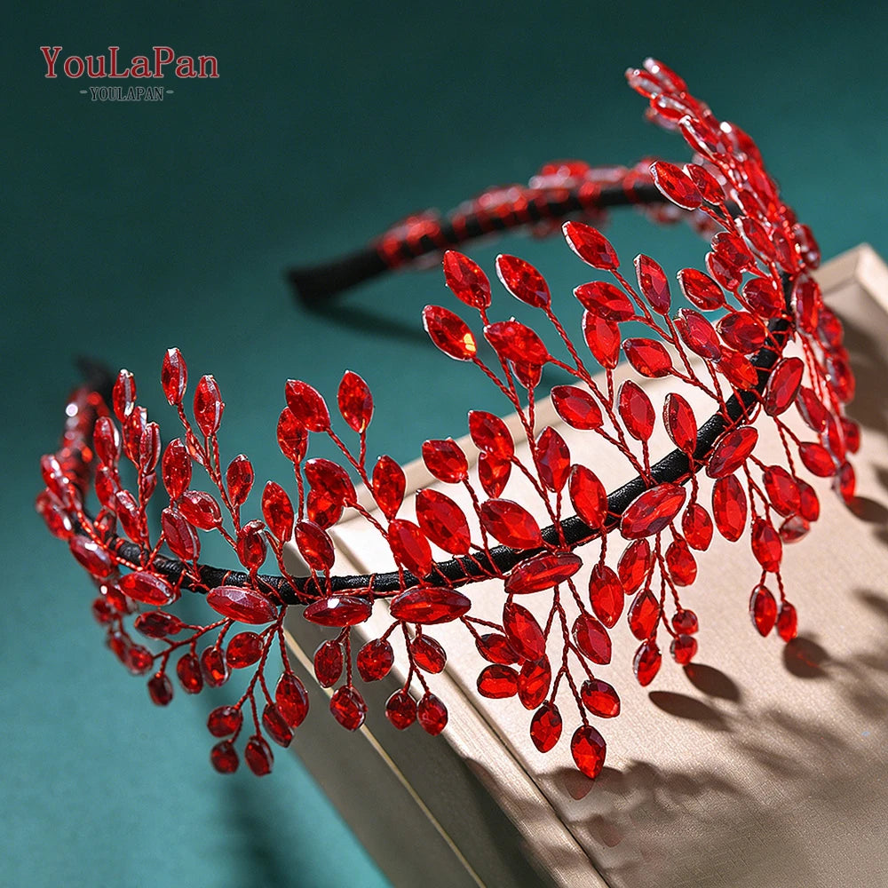 A close-up of a red rhinestone bridal headband with delicate floral accents displayed on a light-colored surface.