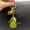 Charm-clés de sac ton or, avec pendentif de poire de cristal vert.