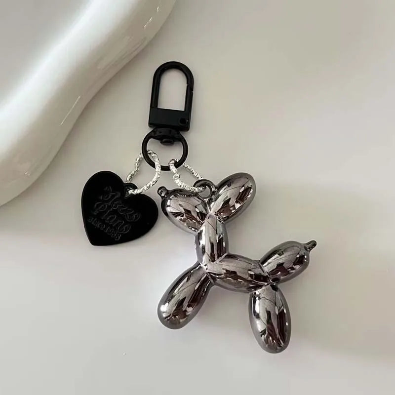 A silver, textured cartoon dog keychain with a heart-shaped charm and black keyring.
