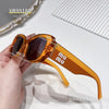 A pair of amber-colored polarized fashion sunglasses with gold accents resting on a hand.