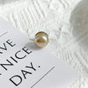 A close-up of a single pearl button resting on a white card against a textured white background.