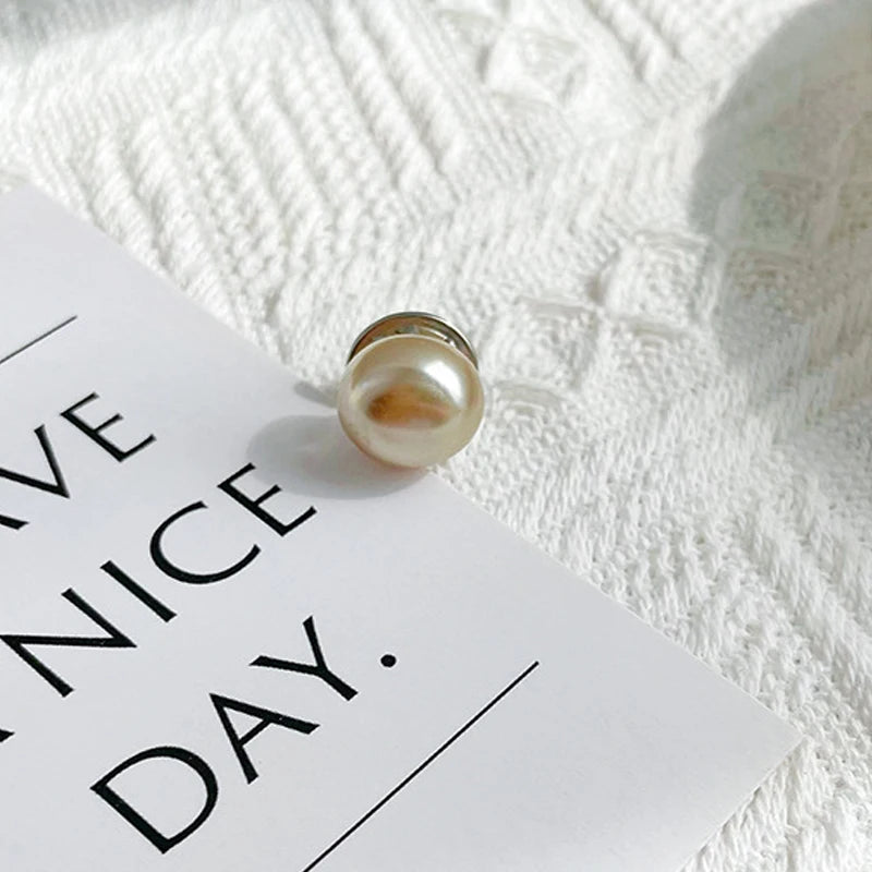 A close-up of a single pearl button resting on a white card against a textured white background.