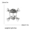 Broche calavera de strass plateado con huesos decorativos y estructura facial detallada
