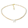 A delicate necklace made of mother of pearl beads with crystal accents, featuring a silver initial charm.
